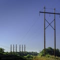 Electric power poles, pylons and transmission lines over the meadow Royalty Free Stock Photo