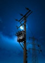 Electric power pylon cables at night blue hour crescent moon sky. High voltage electricity substation on wooden pole tower Royalty Free Stock Photo