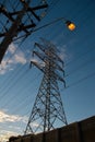 Electric power pylon and a street light pole against a blue sky Royalty Free Stock Photo