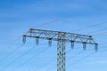 Electric power transmission concept. Selective focus on a electricity supply pylon and the high voltage power lines against a blue Royalty Free Stock Photo