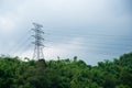 Electric Power Transmission Tower with High Voltage Line on The Top of Mountain Cover with Rain Forest Under Cloudy Sky Royalty Free Stock Photo