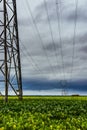 Electric power transmission lines against cloudy sky and green field, France