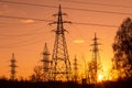 Electric powerlines. High voltage power lines, pylons over sunset orange red sky with sun