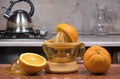 Electric press juicer with cut orange on kitchen table. Manual juice extractor. Juicing oranges