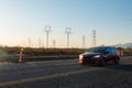 Electric pylons at sunset. Cars drive by on street. Royalty Free Stock Photo