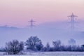 Electric pylons in the Tuscan countryside covered in fog and smog shortly after the dawn of a new day, Bientina, Italy Royalty Free Stock Photo