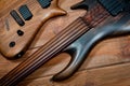 Electric rhythm guitar and five-string bass photographed on a wooden surface