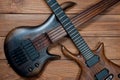 Electric rhythm guitar and five-string bass photographed on a wooden surface