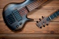Electric rhythm guitar and five-string bass photographed on a wooden surface