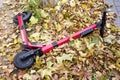 Electric scooter left on the ground. Red escooter on the autumn leaves