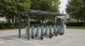 Electric scooters are parked at a docking station with a modern canopy structure. The Royalty Free Stock Photo