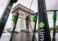 Electric scooters parked and traffic passing in front of Arc de Triomphe in Paris