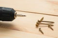 Electric screwdriver on a wooden table. Side view of the black metallic screws, electric screwdriwer on the wodden boards