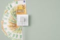Electric socket with connected power plug and Euro banknotes arround it. Electricity cost and expensive energy concept