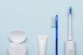 Electric sonic toothbrush with dental floss toothpaste and classic tooth brush on blue Royalty Free Stock Photo