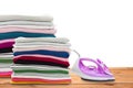 Electric steam iron and Pile of colorful clothes on wooden floor. Royalty Free Stock Photo