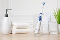 Electric toothbrush, glass of water and toiletries on wooden table Royalty Free Stock Photo