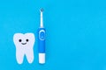 Electric toothbrush, toothpaste, a tooth carved out of felt with a smiling cartoon face. Blue background. Flat lay. The concept of Royalty Free Stock Photo