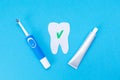 Electric toothbrush, toothpaste, a tooth cut out of felt with a green ok icon. Blue background. Flat lay. The concept of modern Royalty Free Stock Photo