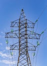 Electric tower with transparent turquoise high voltage insulators or isolator in sunlight on electric tower on blue sky background