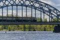 An electric train rides on a bridge crossing a river. Passenger train on the railway bridge Royalty Free Stock Photo