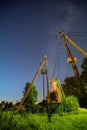 Electric transformer in forest. Night starry sky with glowing stars and meteoric track trail. Power lines in starry sky Royalty Free Stock Photo