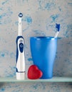 Electric, and usual toothbrush in glass, small heart Royalty Free Stock Photo