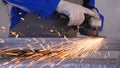 Craftsman sawing metal with disk grinder in workshop. Grinding metal with sparks flying. Electric wheel grinding on Royalty Free Stock Photo