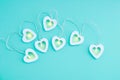 Electric white garland with glowing lights in the form of hearts on turquoise background