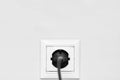 Electric white socket and one plugged in power cord on white wall background Royalty Free Stock Photo