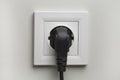 Electric white socket and one plugged in power cord on white wall background Royalty Free Stock Photo