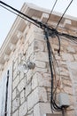 Electric wires attached on an old stone house. Old architecture. Electricity transmission. Light bulb on the building. Street ligh Royalty Free Stock Photo