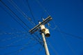 Electric wires and pillar on blue sky background. Tangle of electrical wires. Electric pillar with too many connection Royalty Free Stock Photo