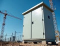 Electrical control box sits at a construction site with cranes in background. Utility equipment installation underway for power Royalty Free Stock Photo