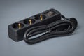 Electrical cord with three outlets and a power switch. Brand new black power cord with plugs, isolated on gray Royalty Free Stock Photo