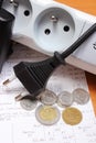 Electrical cords disconnected from power strip and electricity bill with coins Royalty Free Stock Photo