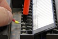 An electrical engineer connects a wire to a PLC terminal block.