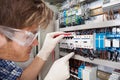 Electrical engineer examining fusebox with multimeter probe