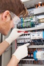 Electrical engineer examining fusebox with multimeter probe Royalty Free Stock Photo