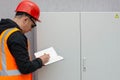 Electrical engineer inspects the switchboard, writing down the faults in a notebook. Maintenance of the transformer