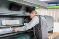 Electrical engineer operator repairs large industrial printer and plotter machine