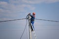 Electrical engineer performs wiring on a high pole standing on the stairs. high-rise electrical work. podkluchenie house to the