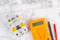 Electrical engineering drawings, modular circuit breaker and digital multimeter. Royalty Free Stock Photo