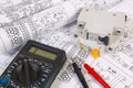 Electrical engineering drawings, modular circuit breaker and digital multimeter. Royalty Free Stock Photo