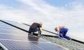 Electrical engineers mans are working installing solar panels on solar station on house roof against blue sky. Building a solar Royalty Free Stock Photo