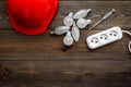 Electrical installation, wiring work concept. Hard hat, bulb, socket outlet on dark wooden background top view copy Royalty Free Stock Photo