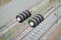 Electrical insulators on the contact wires on the background of a blurred railway track. Macro photo with selective focu Royalty Free Stock Photo