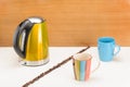 Kettle with mugs and handful coffee beans on the wood and marble background