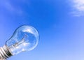 Eelectrical light bulb in hand on blue sky background. Hand holding light bulb on a background sky and sun. Royalty Free Stock Photo