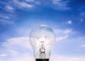 Eelectrical light bulb in hand on blue sky background. Hand holding light bulb on a background sky and sun. Royalty Free Stock Photo